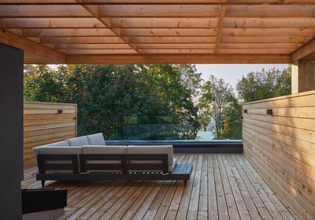 The roof deck, partially covered by a wood trellis, provides spectacular views out over the lake